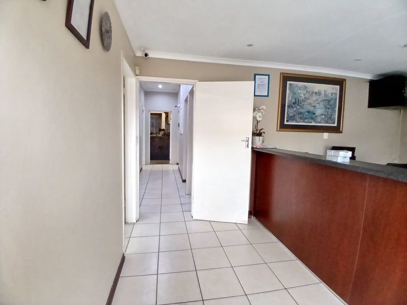 Commercial reception area featuring a built-in service counter, tiled flooring, and access to a rear hallway.