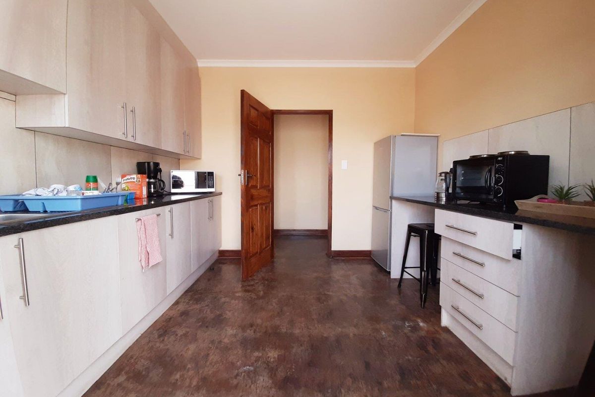 A functional kitchen featuring light-toned built-in cabinetry, dark granite countertops, and a tiled backsplash, providing a practical workspace for commercial or residential use.