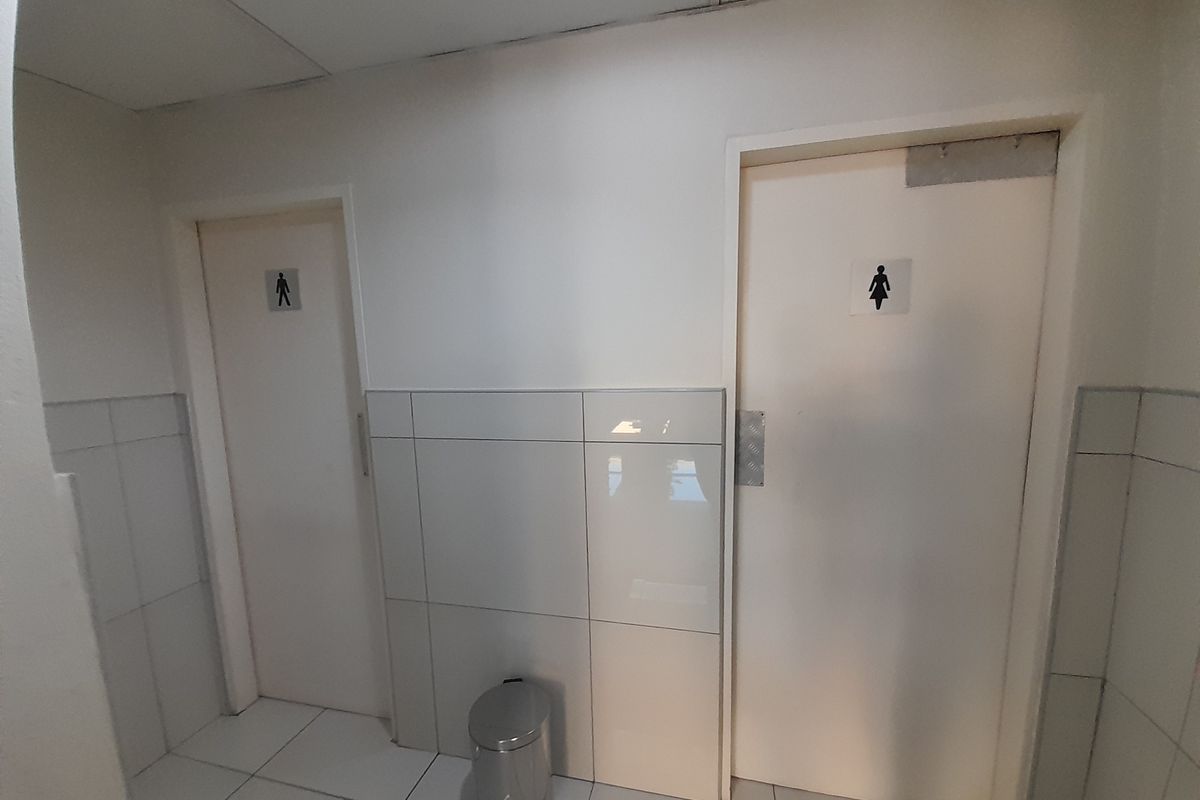 A functional office restroom facility featuring separate male and female access doors with tiled walls and flooring.