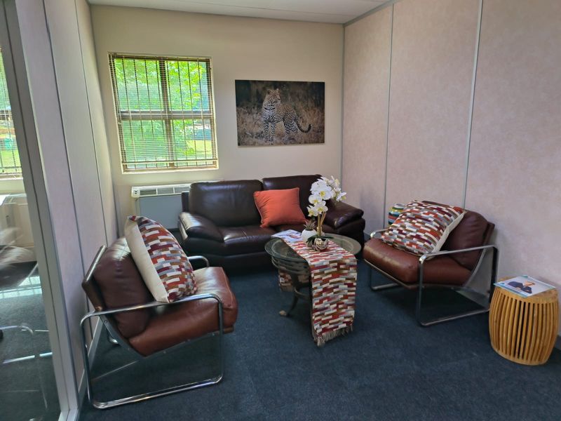A compact office space featuring modular partition walls, carpeted flooring, and a wall-mounted HVAC unit for climate control.