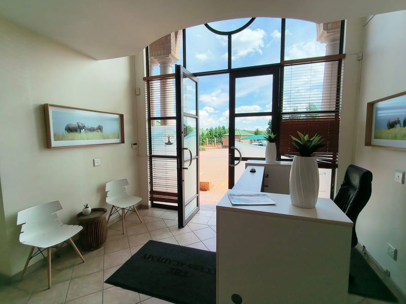 Bright office reception area featuring large glass entrance doors, tiled flooring, and an arched ceiling detail, creating a welcoming and professional entry space.