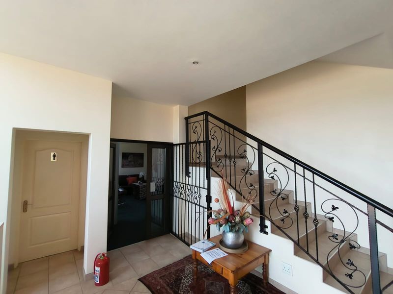 Office building entrance foyer featuring a tiled staircase with decorative wrought iron railing and a secure internal gate.