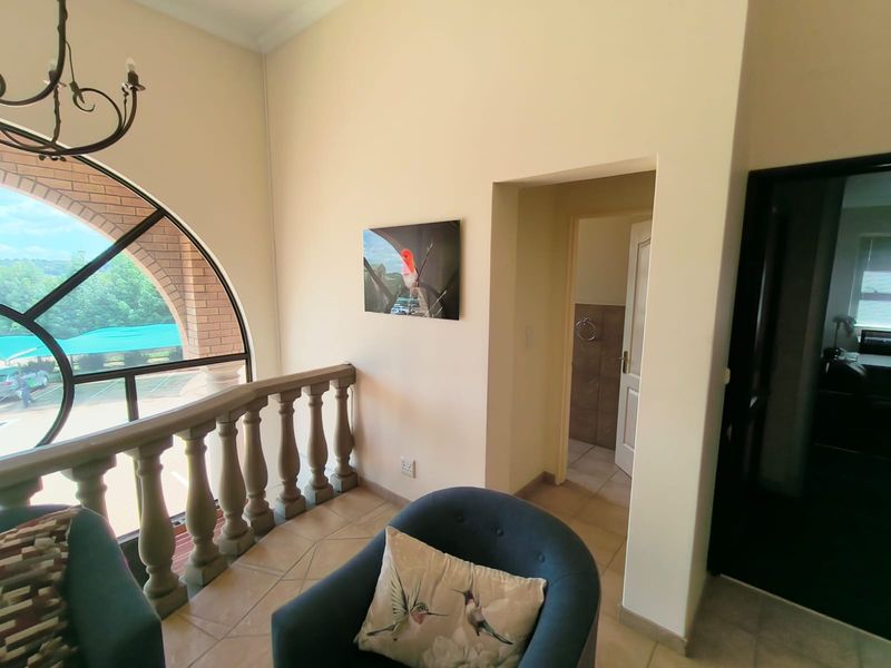 Office space featuring an arched window with a stone balustrade, tiled flooring, and access to an adjoining room.