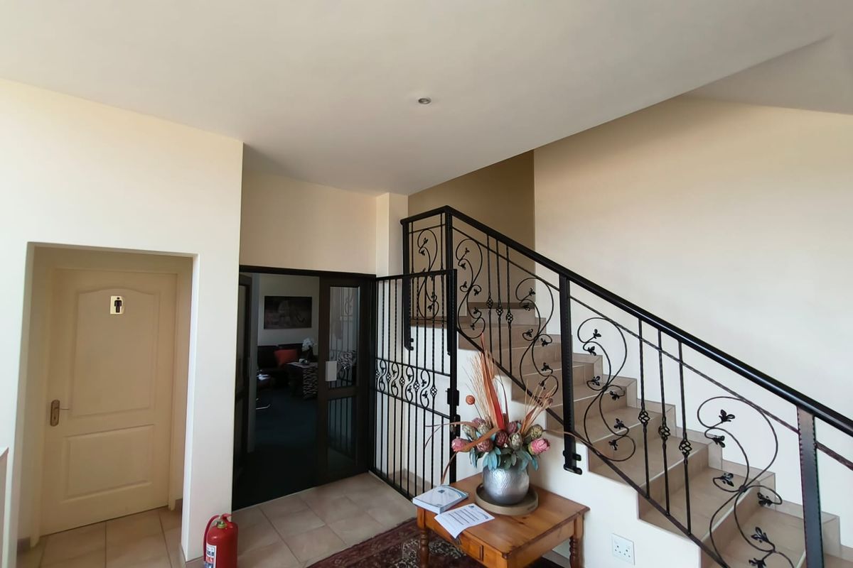 Office building entrance foyer featuring a tiled staircase with decorative wrought iron railing and a secure internal gate.