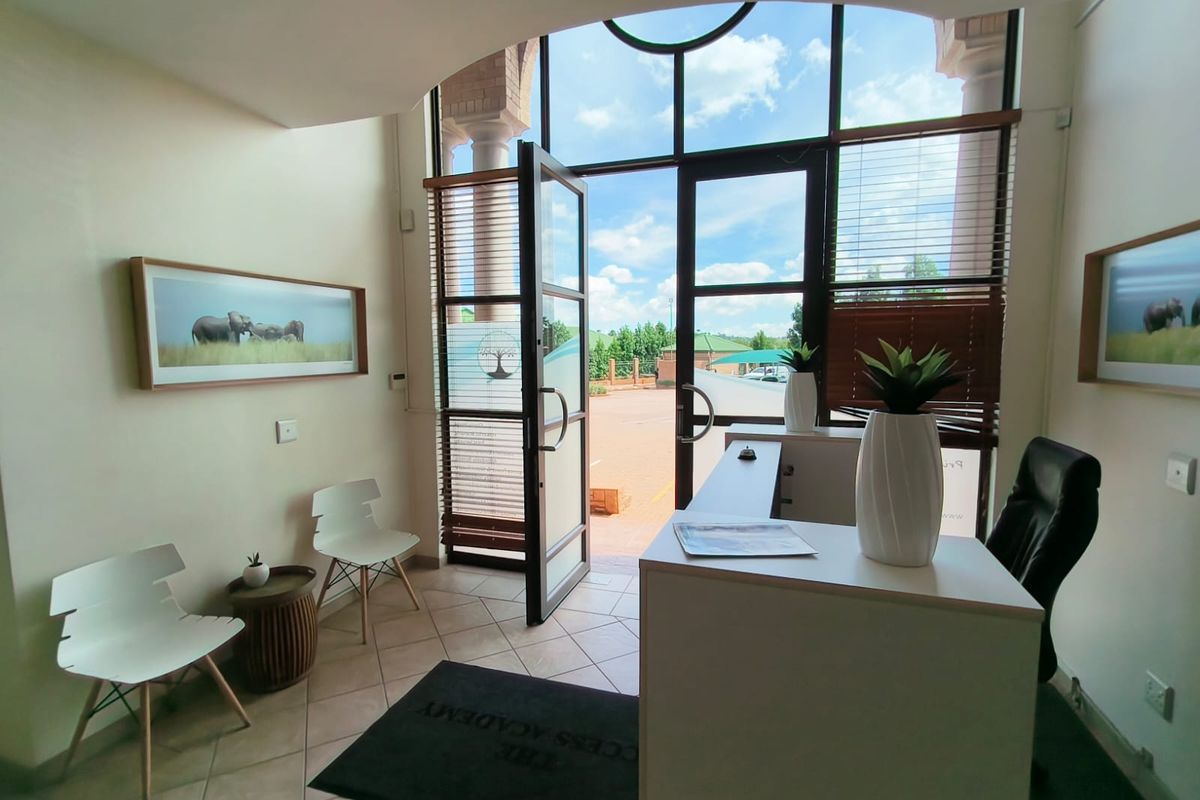 Bright office reception area featuring large glass entrance doors, tiled flooring, and an arched ceiling detail, creating a welcoming and professional entry space.