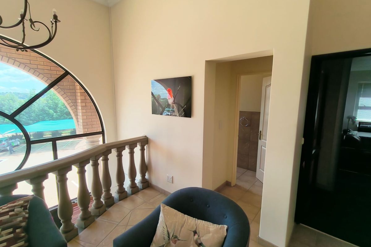 Office space featuring an arched window with a stone balustrade, tiled flooring, and access to an adjoining room.