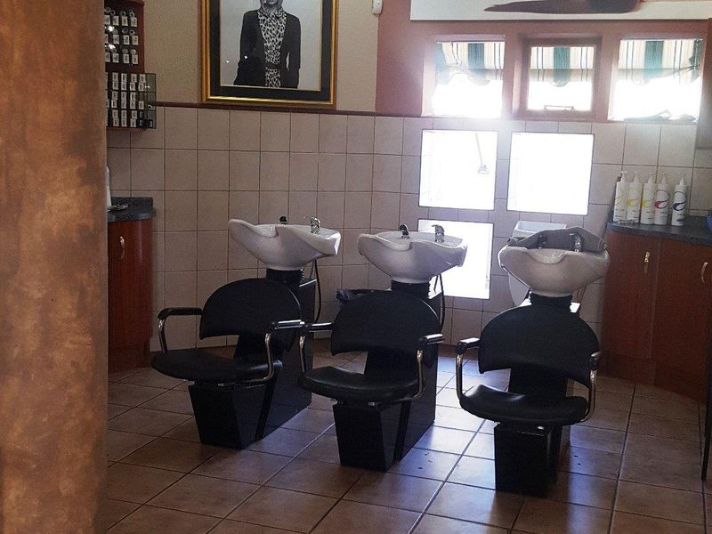 A commercial salon space featuring three professional wash basins, tiled flooring, and built-in cabinetry, suitable for hair care services.