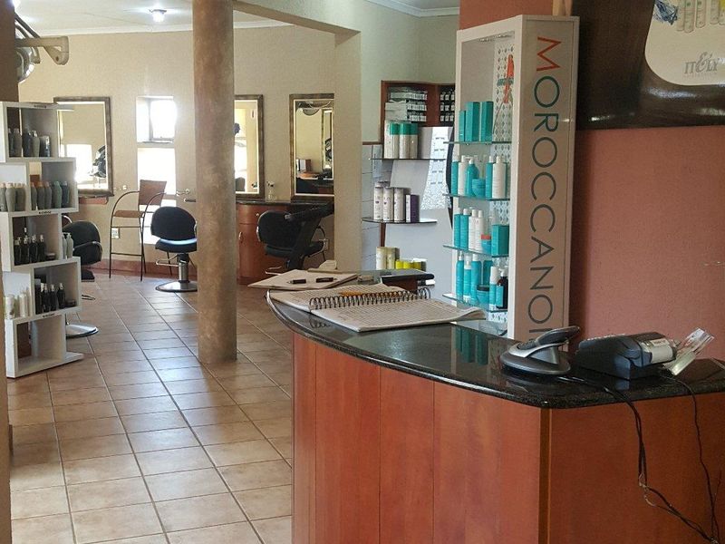 Open-plan commercial salon space featuring a built-in reception desk, ceramic tile flooring, and recessed lighting throughout the functional work area.
