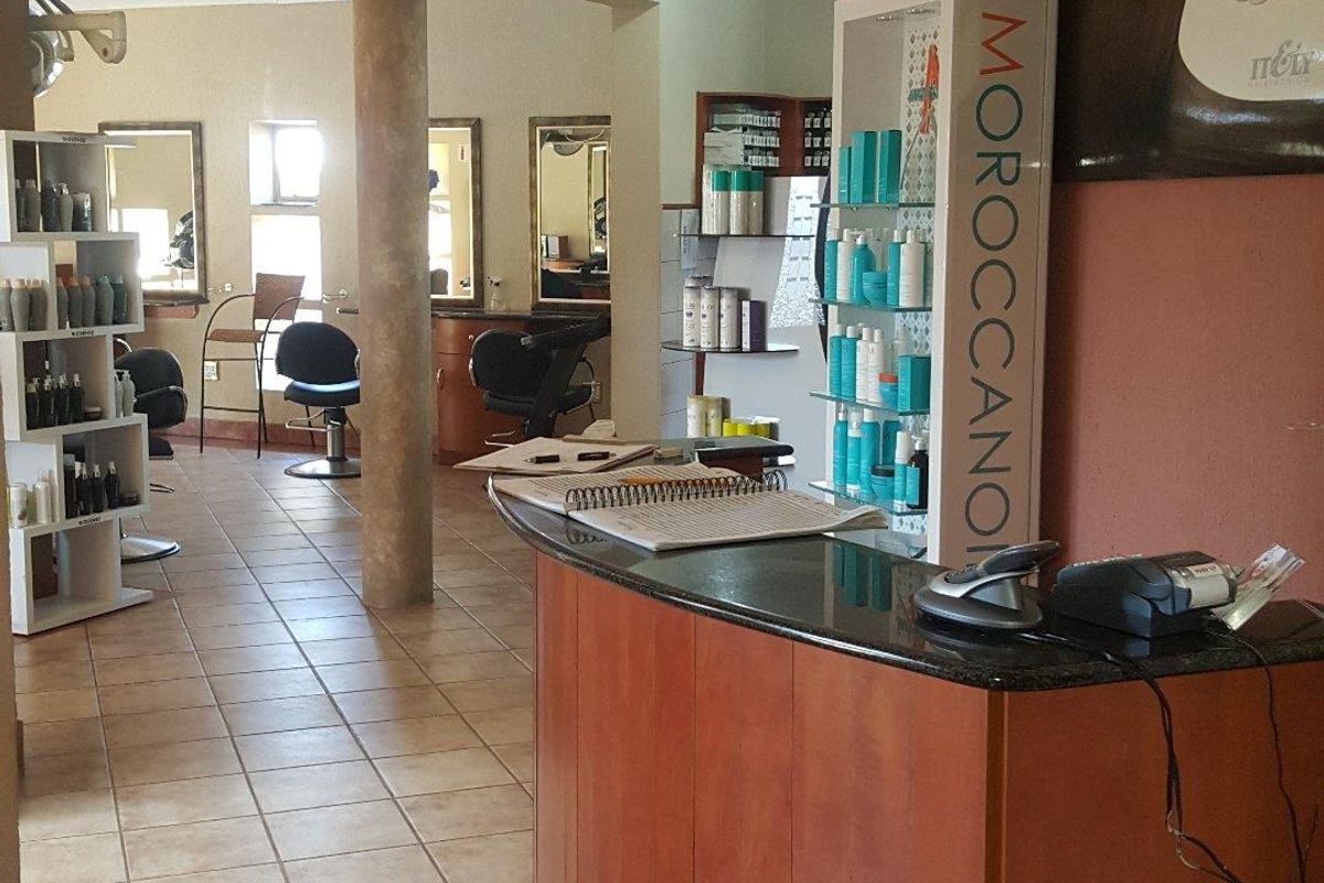 Open-plan commercial salon space featuring a built-in reception desk, ceramic tile flooring, and recessed lighting throughout the functional work area.
