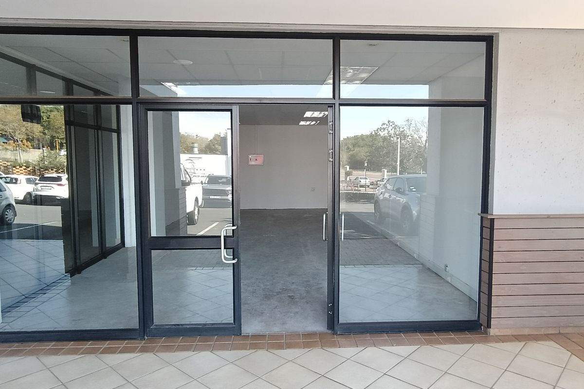 Commercial storefront entrance featuring an aluminium-framed glass facade and door, leading into an open-plan interior space with concrete flooring.