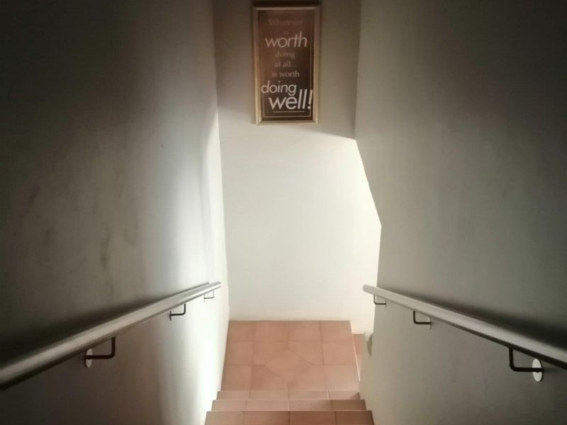 A functional staircase featuring tiled steps and dual wall-mounted handrails, providing access between levels in this commercial property.