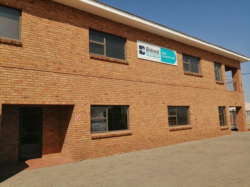 A two-story commercial building featuring a face brick facade, aluminium window frames, and a paved driveway entrance.