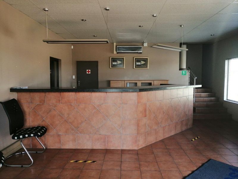 Commercial reception area featuring a tiled service counter, suspended ceiling, and direct access to an internal staircase.