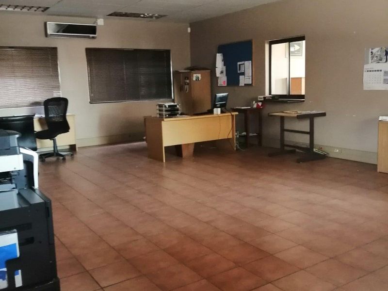 Spacious commercial office area featuring ceramic tiled flooring, suspended ceilings with recessed lighting, and a wall-mounted air conditioning unit.