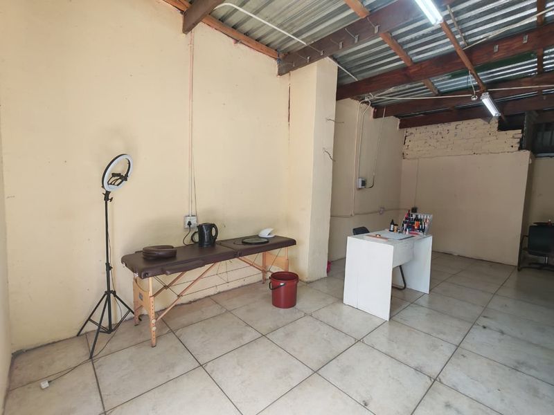 A functional commercial utility space featuring tiled flooring, exposed timber roof beams, and basic electrical infrastructure, suitable for various business or service applications.