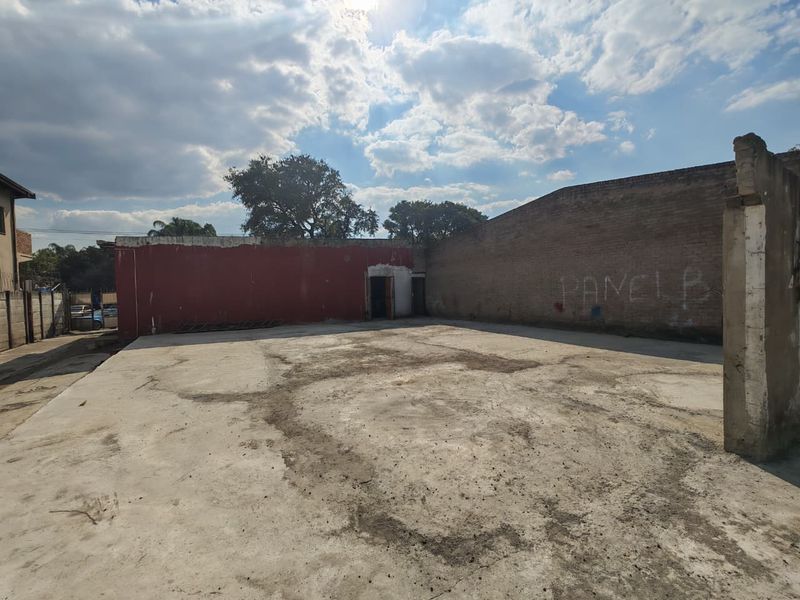 An open-air commercial yard featuring a concrete slab surface and surrounding brick boundary walls, requiring maintenance and surface repairs.
