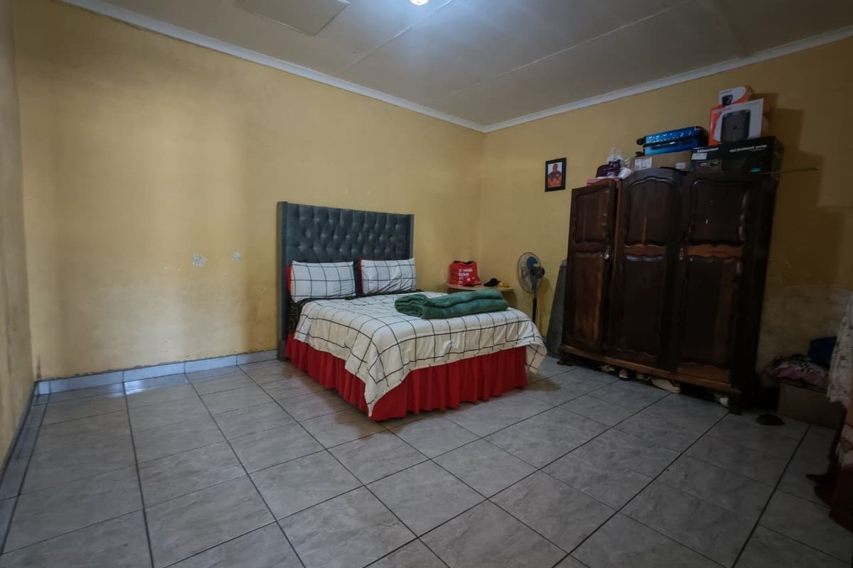 A bedroom featuring tiled flooring and yellow painted walls, requiring cosmetic updates to improve the overall aesthetic and finish.