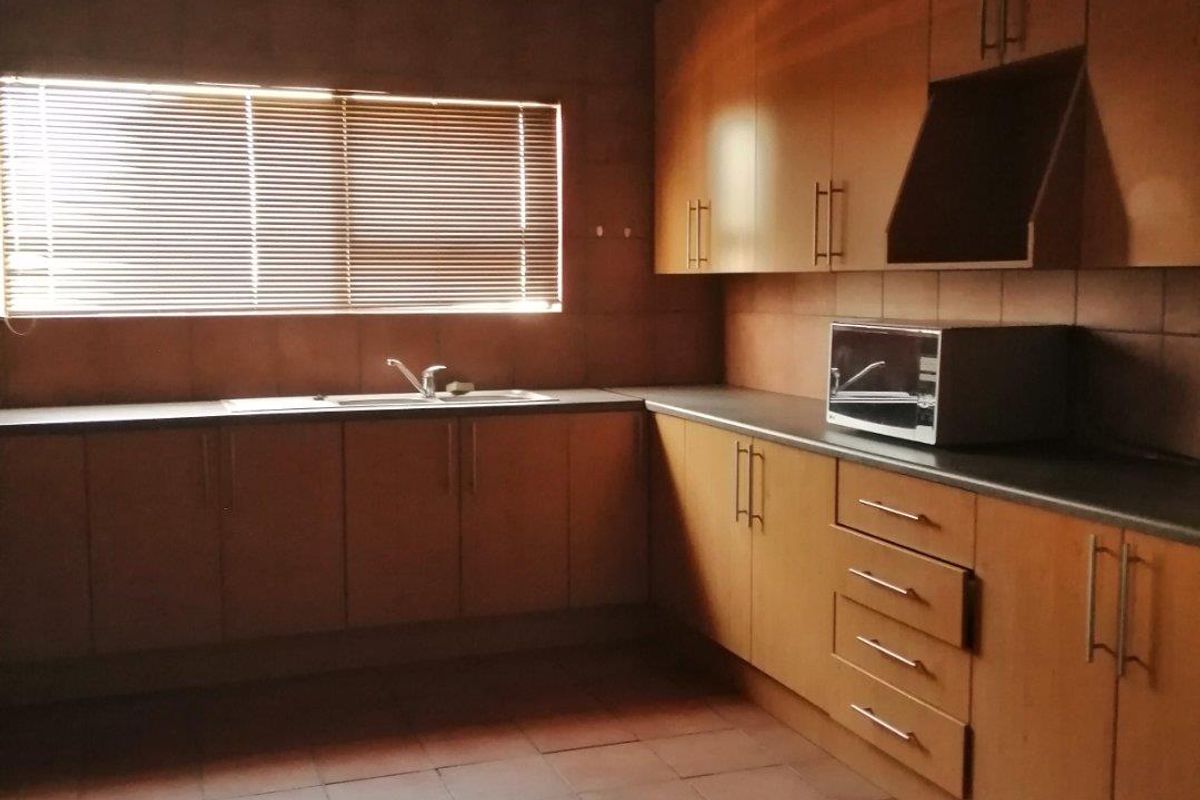 A functional kitchen featuring laminate cabinetry, tiled flooring, and a stainless steel sink, offering a practical layout ready for modernization.