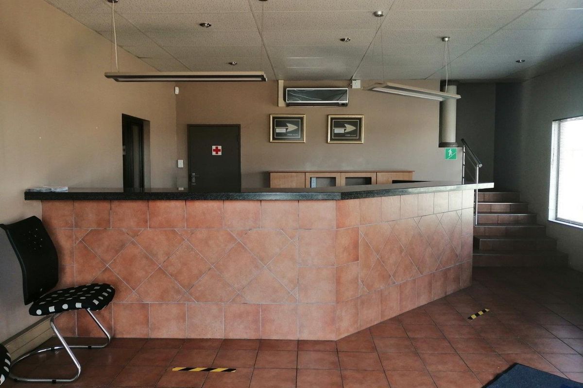 Commercial reception area featuring a tiled service counter, suspended ceiling, and direct access to an internal staircase.