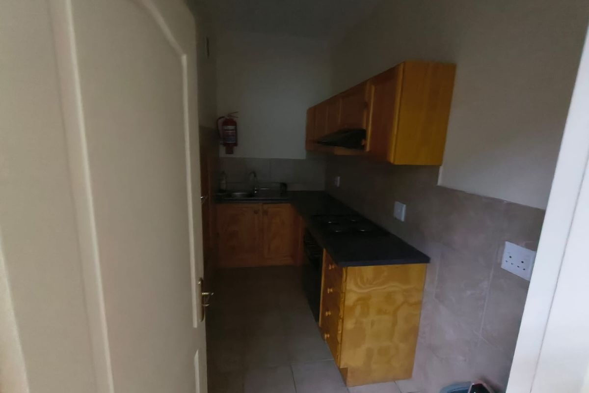 A compact office kitchenette featuring wooden cabinetry, a built-in hob, and a stainless steel sink.