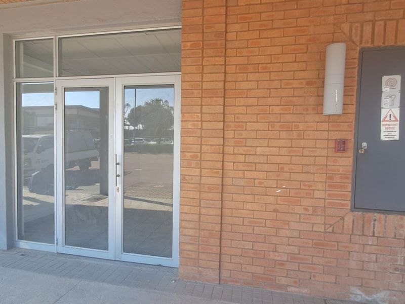 Main entrance to the industrial unit featuring a glass double door, brick exterior wall, and secure utility access.