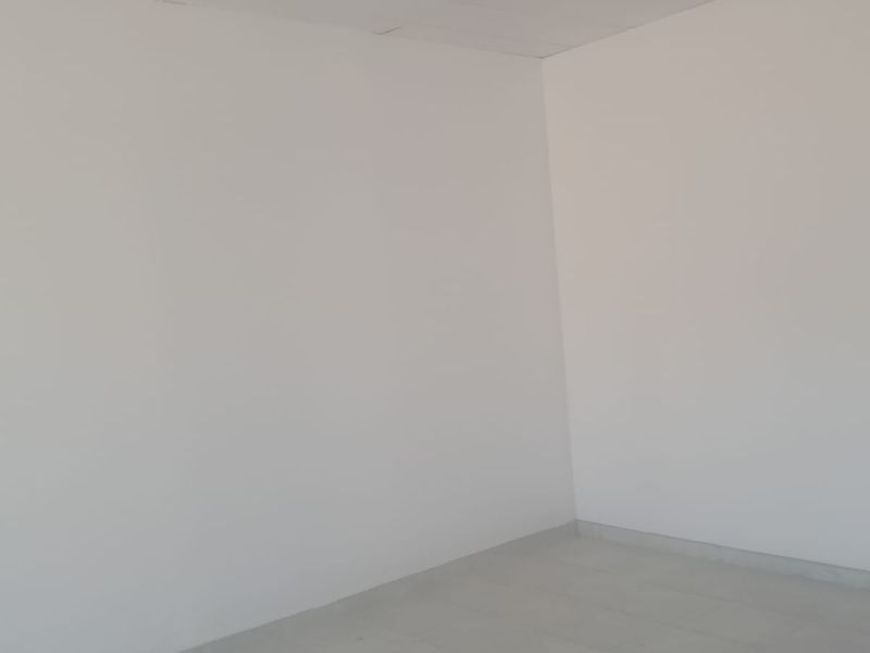 An empty, plain interior space with white walls and tiled flooring, suitable for various industrial or commercial uses.