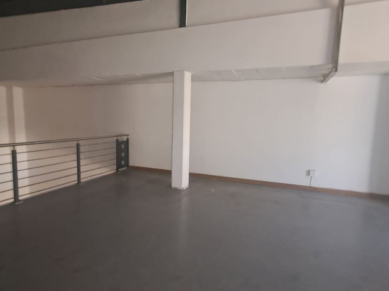 An open-plan mezzanine level featuring concrete flooring, a steel balustrade, and a clean, neutral industrial aesthetic suitable for office or storage use.