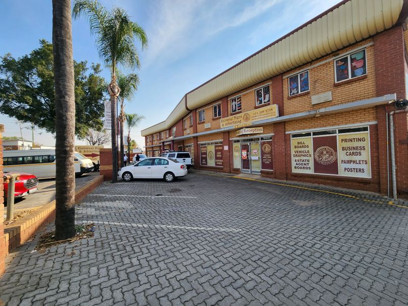 Front exterior view of a commercial office building featuring brick facade, paved parking area, and prominent business signage.