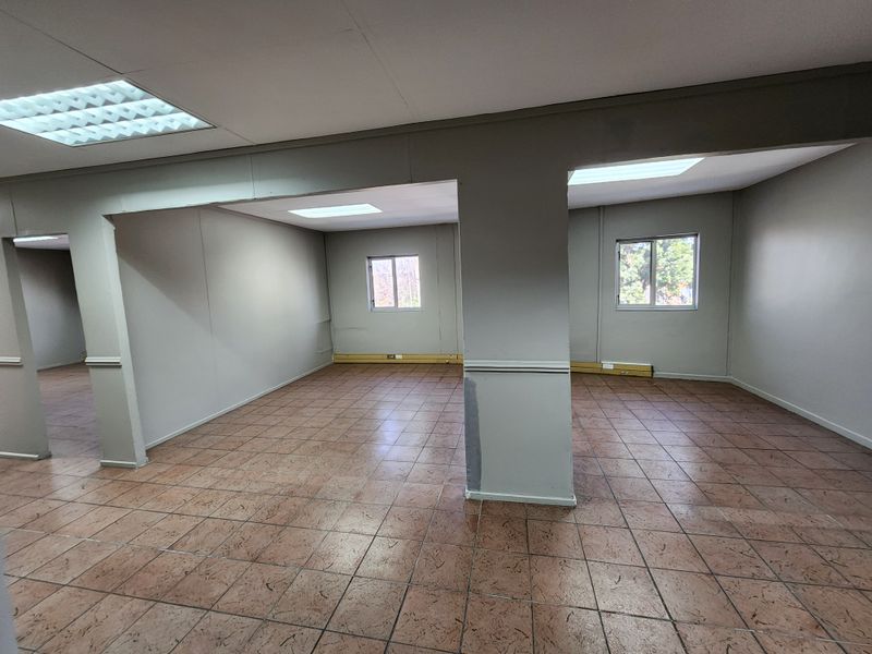 An open-plan office space featuring ceramic tile flooring, recessed lighting, and neutral wall finishes, providing a versatile layout for professional use.