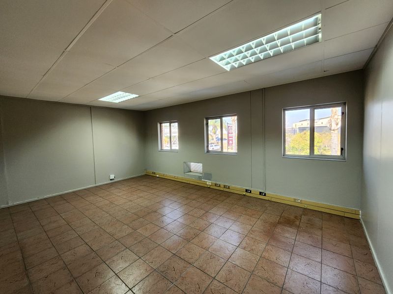 A vacant office space featuring tiled flooring, recessed fluorescent lighting, and perimeter trunking for electrical and data connectivity.
