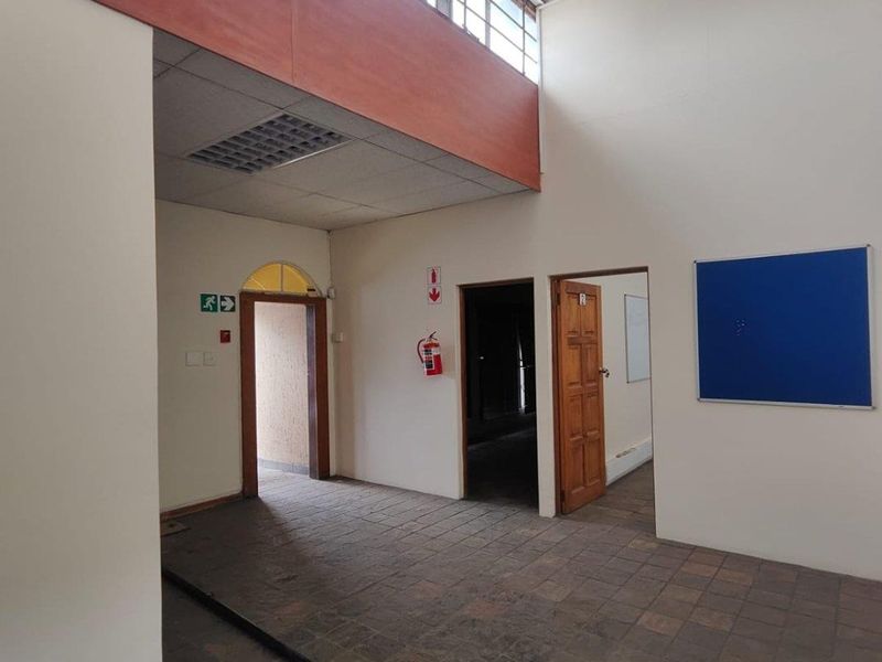 Spacious commercial entry area featuring high ceilings, clerestory windows for natural light, tiled flooring, and multiple access points.