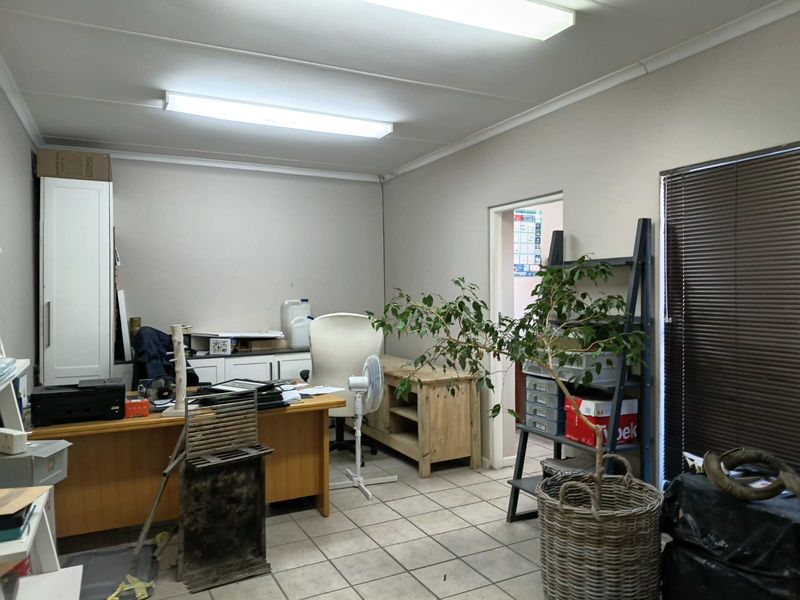 A functional office space featuring tiled flooring, built-in cabinetry, and fluorescent lighting, providing a practical work environment.