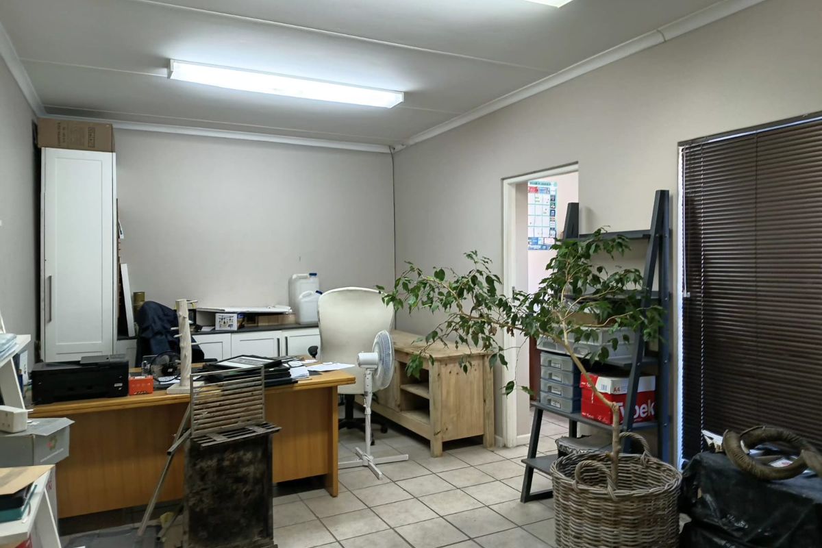 A functional office space featuring tiled flooring, built-in cabinetry, and fluorescent lighting, providing a practical work environment.