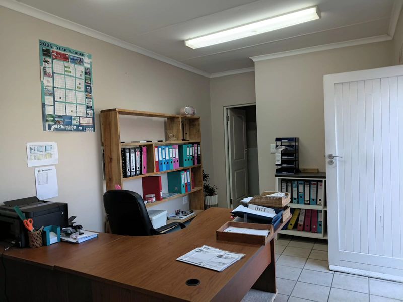 A functional office space featuring tiled flooring, neutral walls, and overhead fluorescent lighting, suitable for a professional work environment.