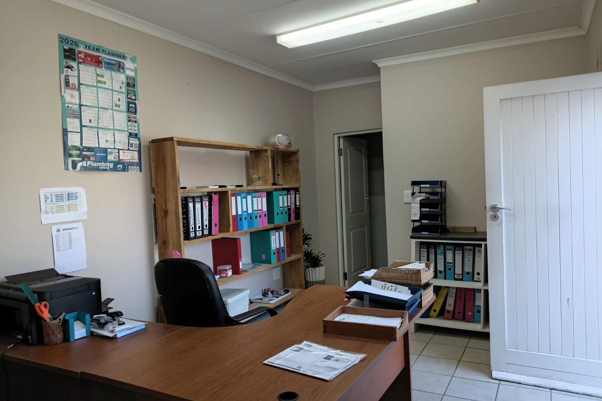 A functional office space featuring tiled flooring, neutral walls, and overhead fluorescent lighting, suitable for a professional work environment.