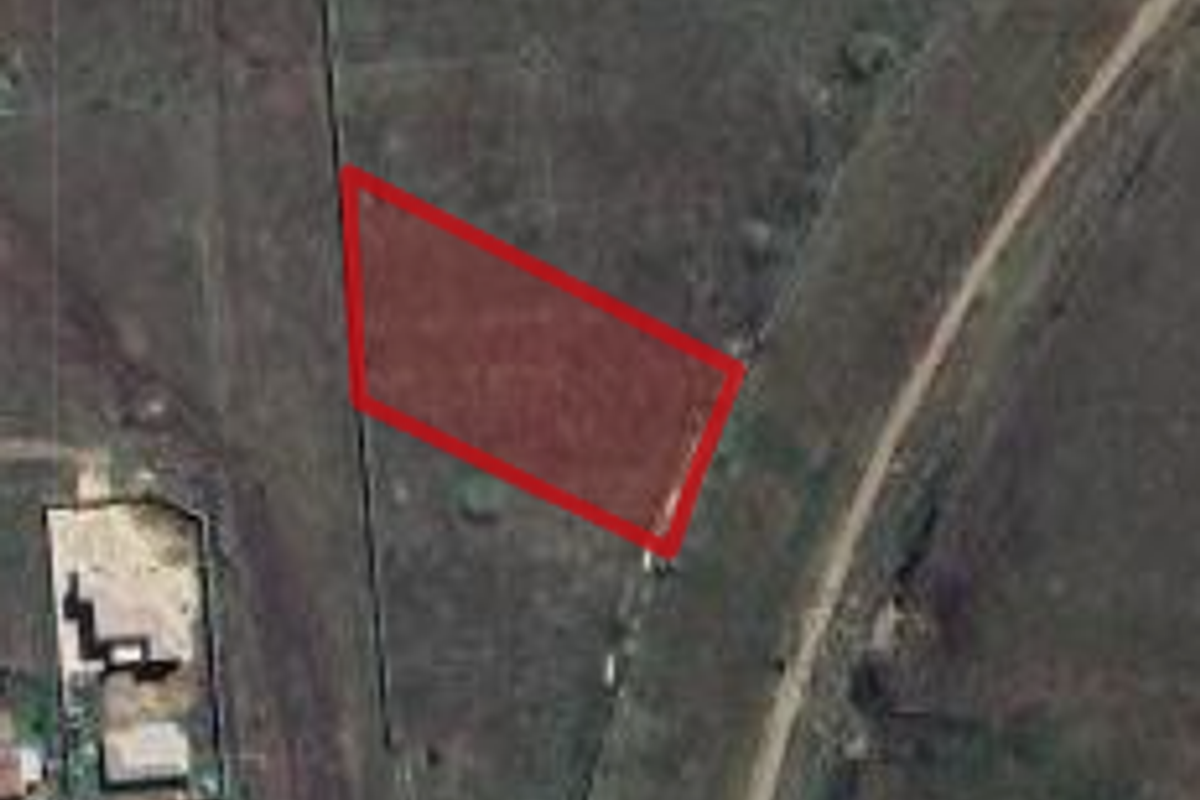 Aerial view of a vacant commercial land plot with perimeter fencing, highlighting the property boundaries.