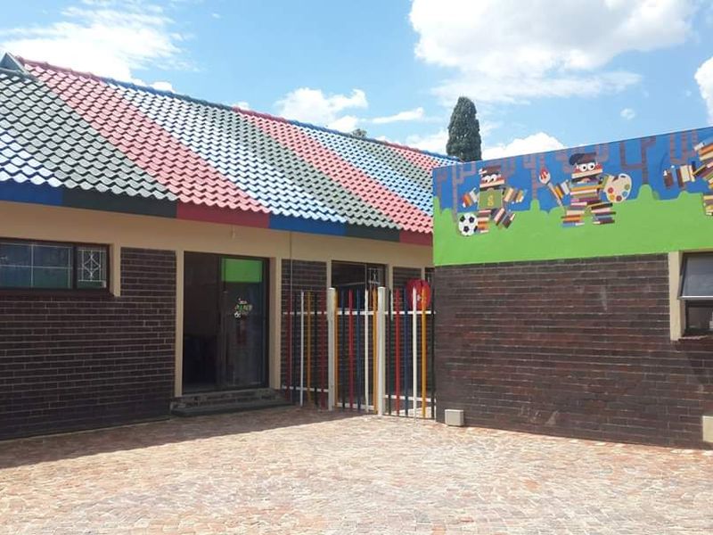 A well-maintained commercial courtyard featuring brick exterior walls, a multi-colored tiled roof, and a decorative mural, providing a secure and functional outdoor space.