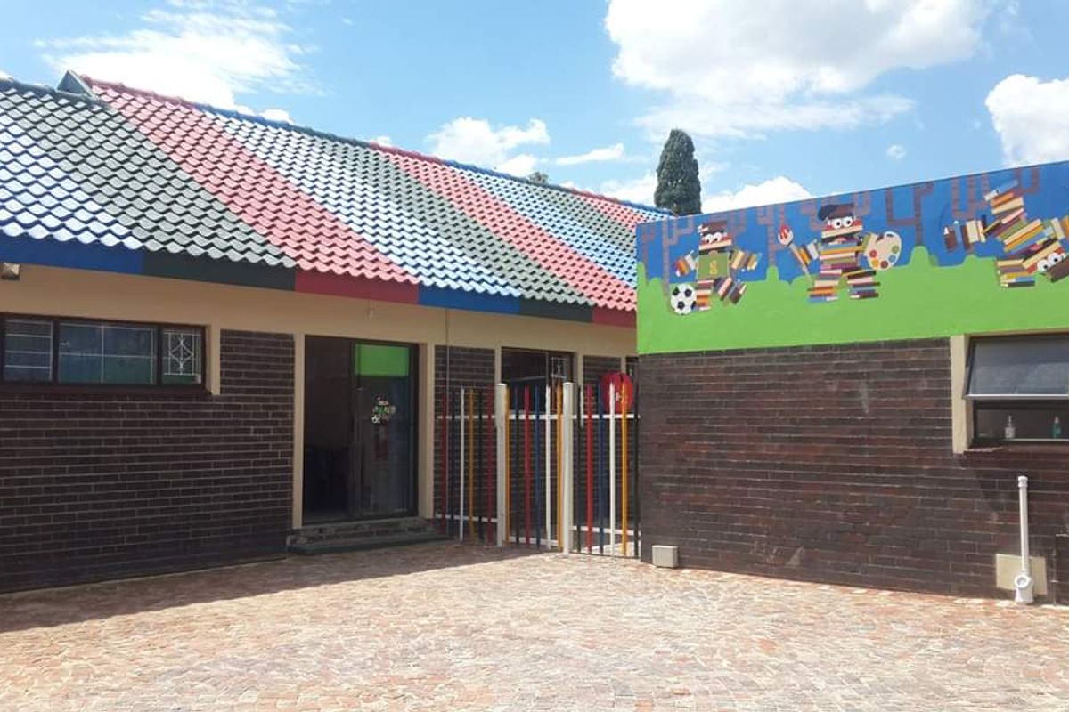 A well-maintained commercial courtyard featuring brick exterior walls, a multi-colored tiled roof, and a decorative mural, providing a secure and functional outdoor space.