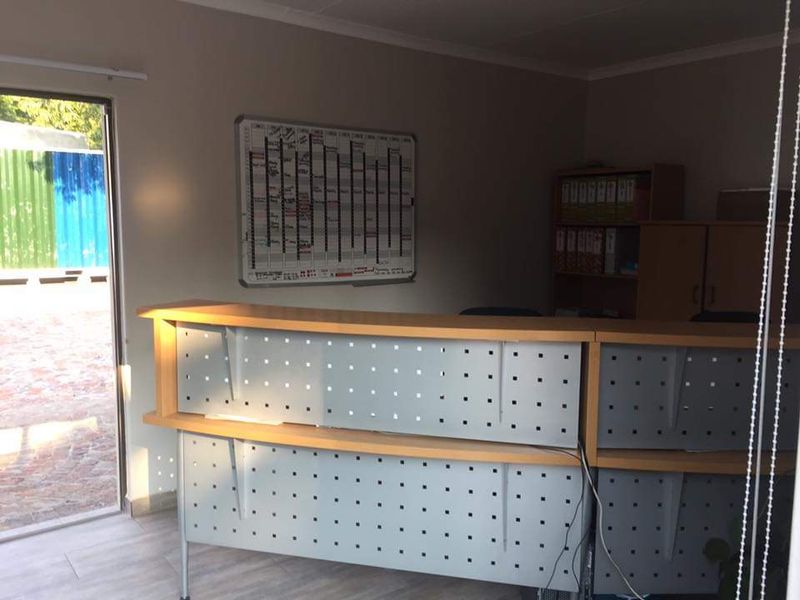 A functional office space featuring a built-in reception desk and tiled flooring, providing a professional environment for administrative tasks.
