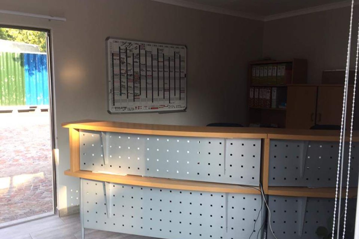 A functional office space featuring a built-in reception desk and tiled flooring, providing a professional environment for administrative tasks.