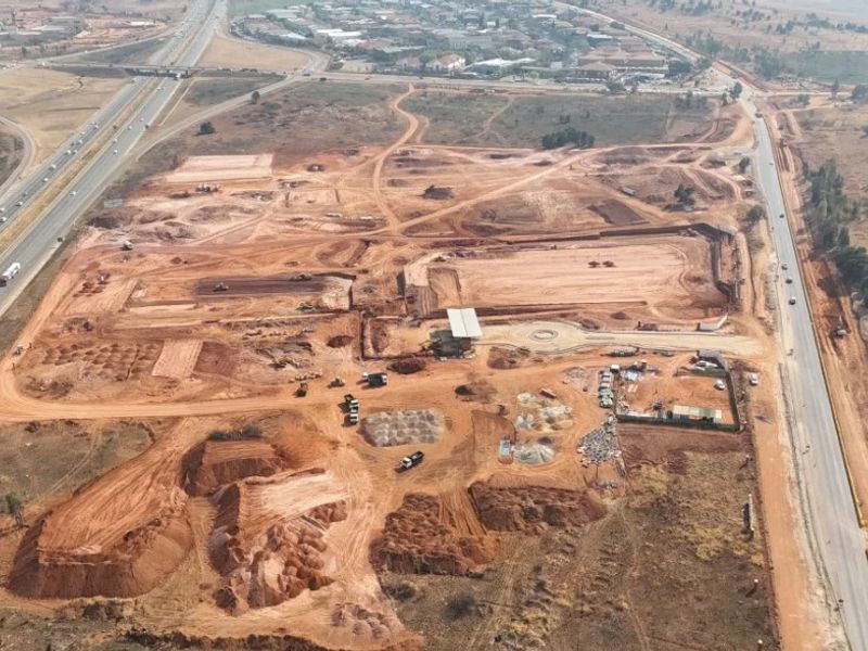 Aerial view of a large industrial development site showing ongoing earthworks, site preparation, and proximity to major highway infrastructure.