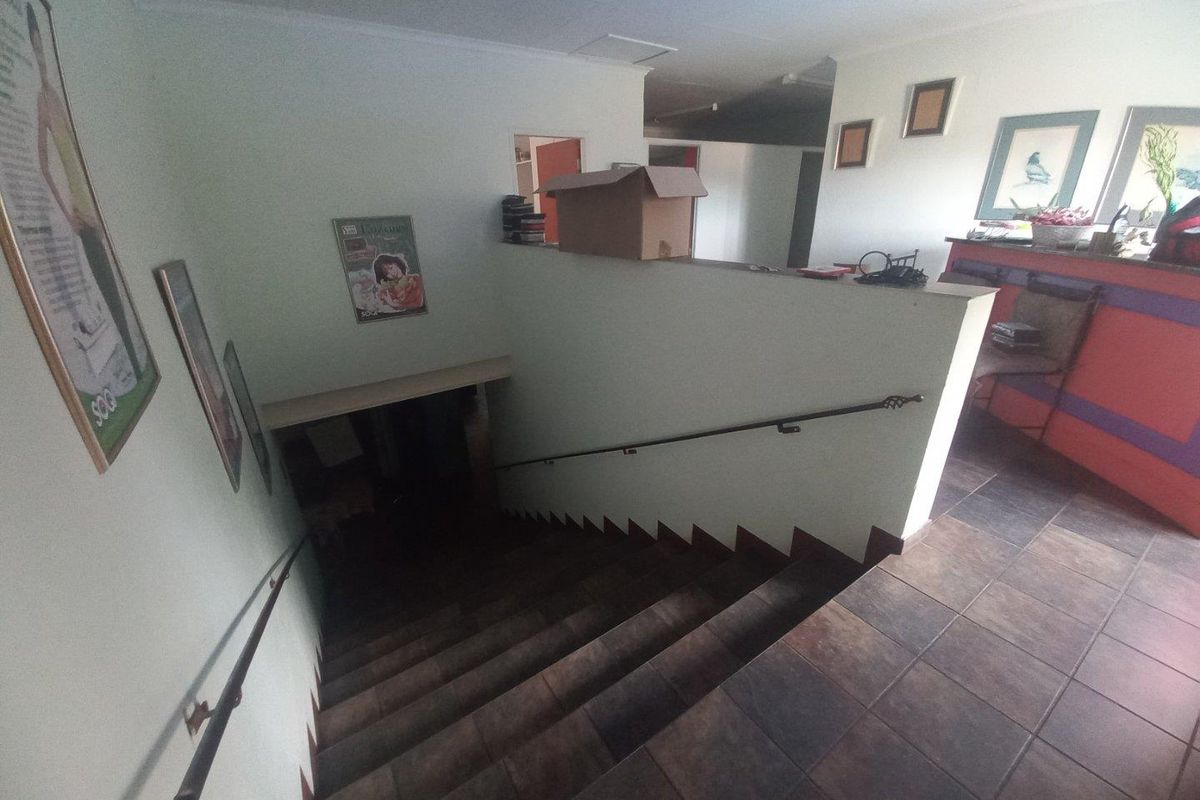 Interior hallway featuring a tiled staircase with wrought iron handrails, providing access between levels in this commercial property.