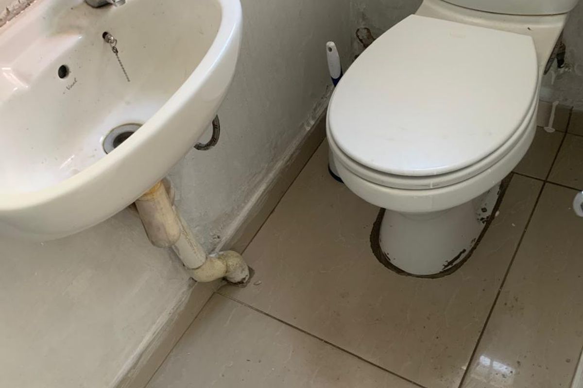 A compact guest bathroom featuring a wall-mounted basin and a standard toilet with tiled flooring.