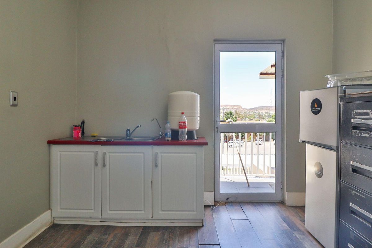 A functional kitchenette area featuring built-in cabinetry, a sink, and direct access to an outdoor balcony space.