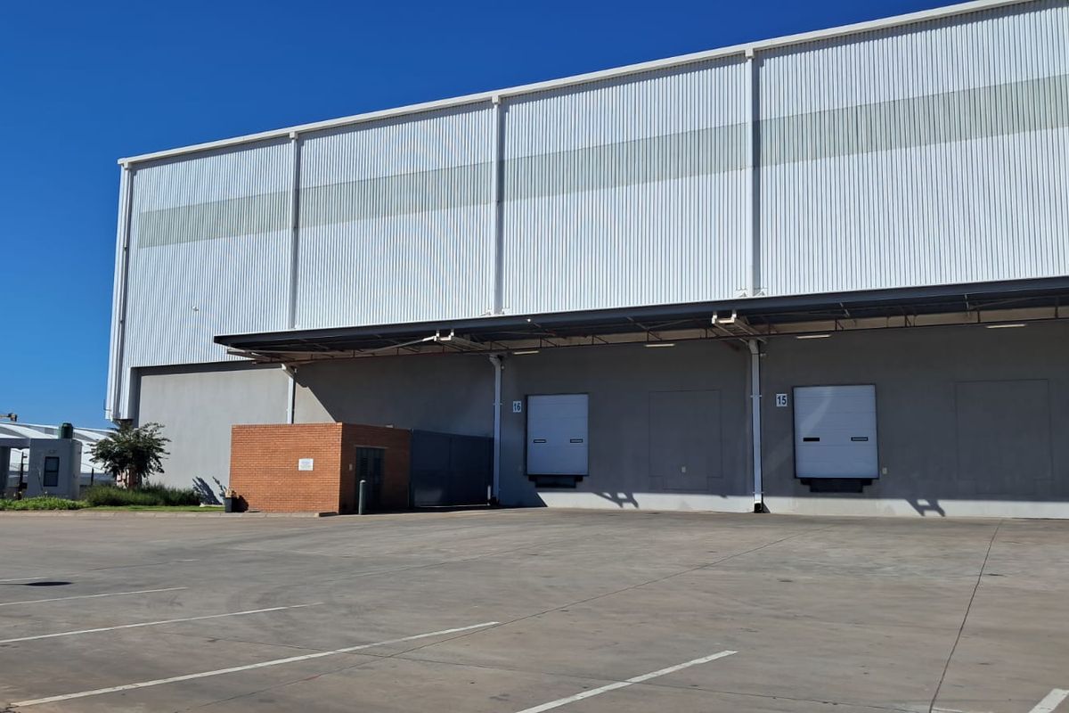 Industrial warehouse exterior featuring multiple loading docks with dock levelers, a protective canopy, and a spacious concrete hardstand area.