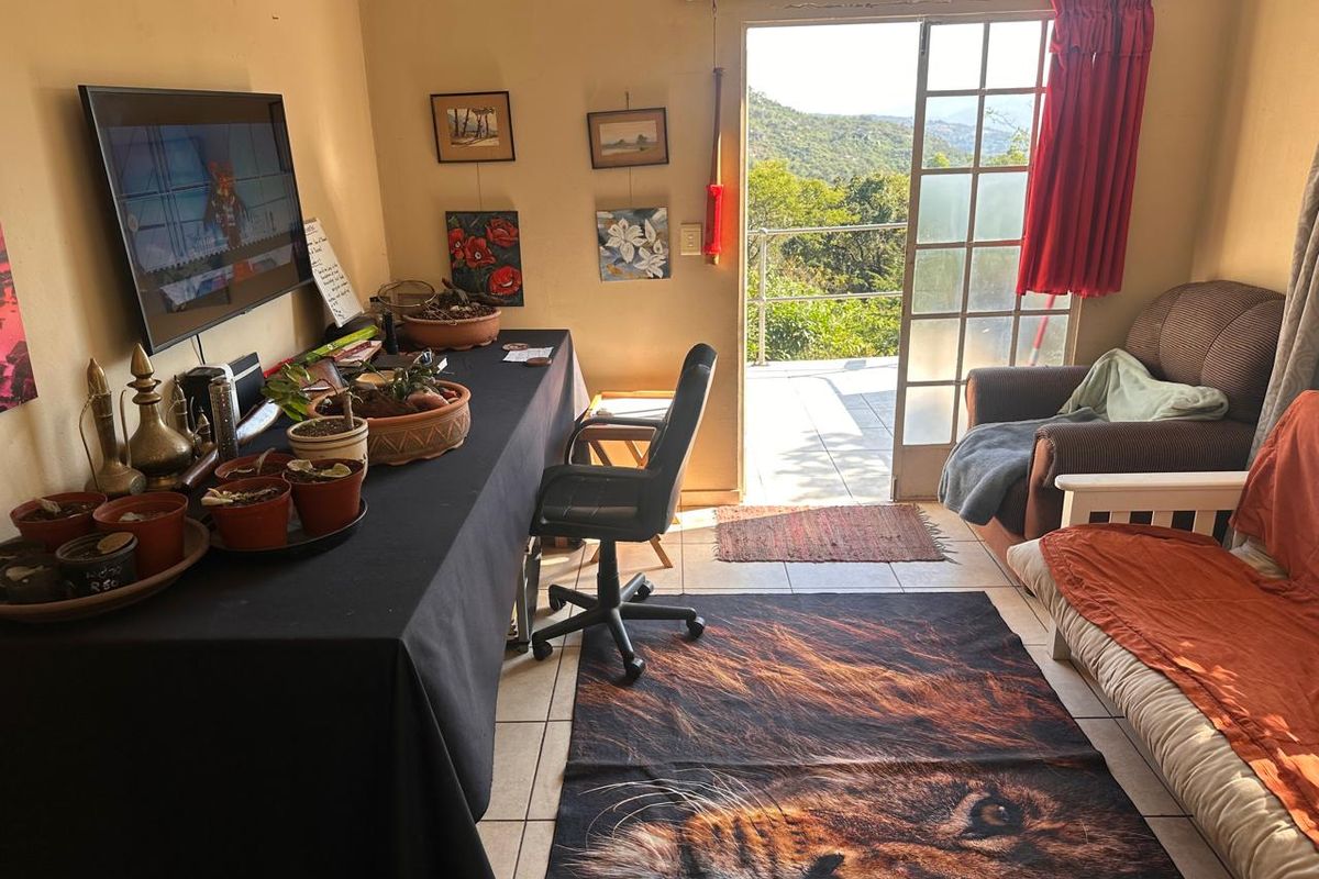 A living area featuring tiled floors and a sliding glass door that opens onto an outdoor patio with scenic views.