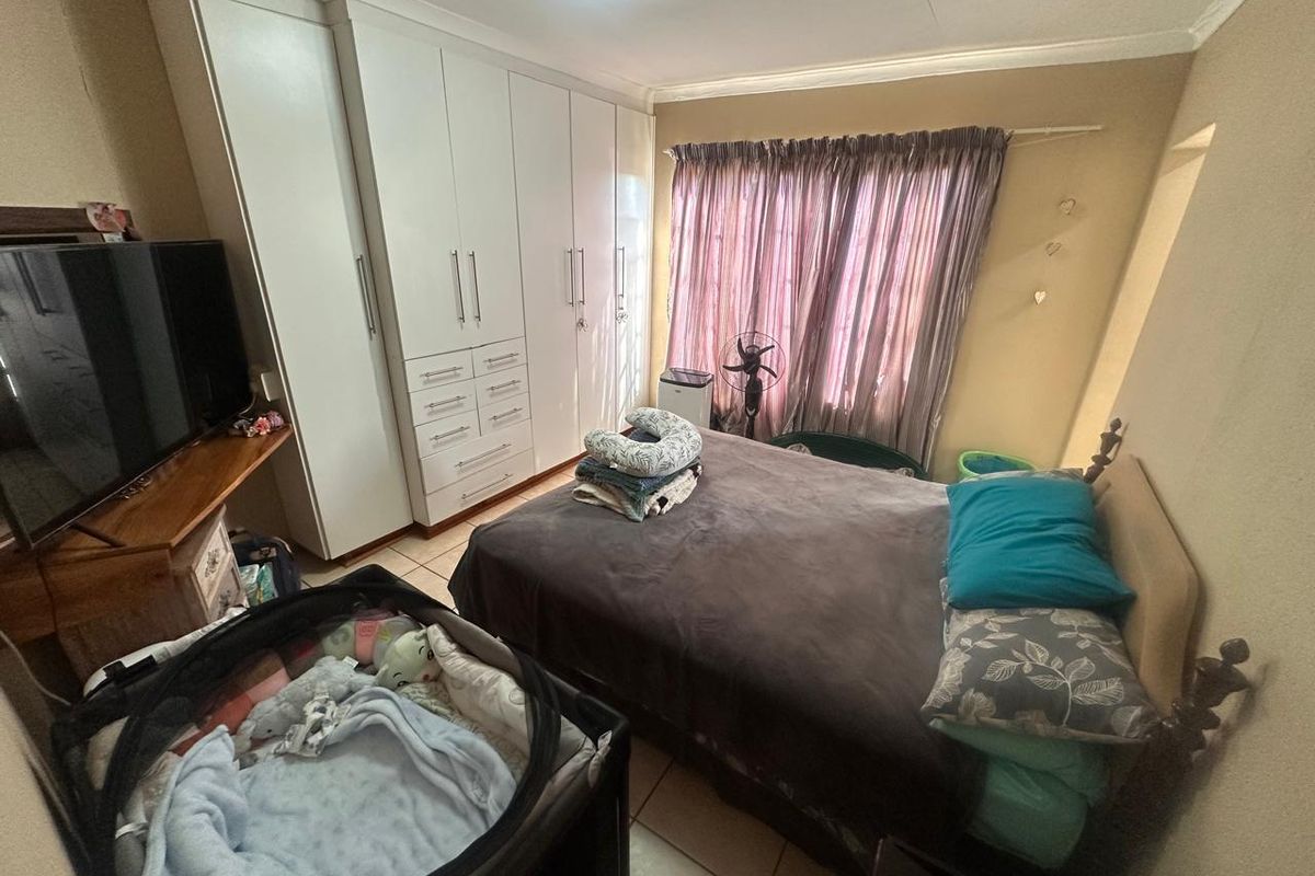 A functional bedroom featuring built-in cupboards and tiled flooring, offering practical storage space and a neutral layout.