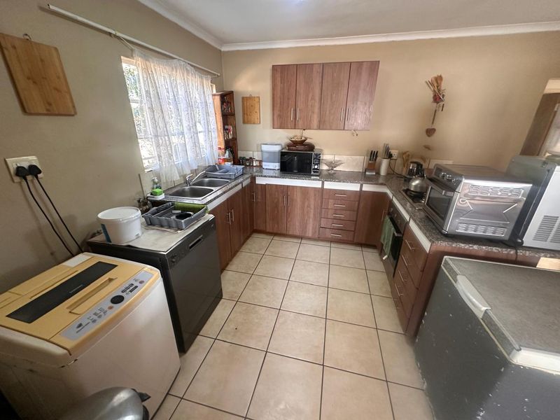 A functional kitchen featuring wood-look cabinetry, granite countertops, double basin sink, and ceramic floor tiles, offering a practical layout for daily meal preparation.