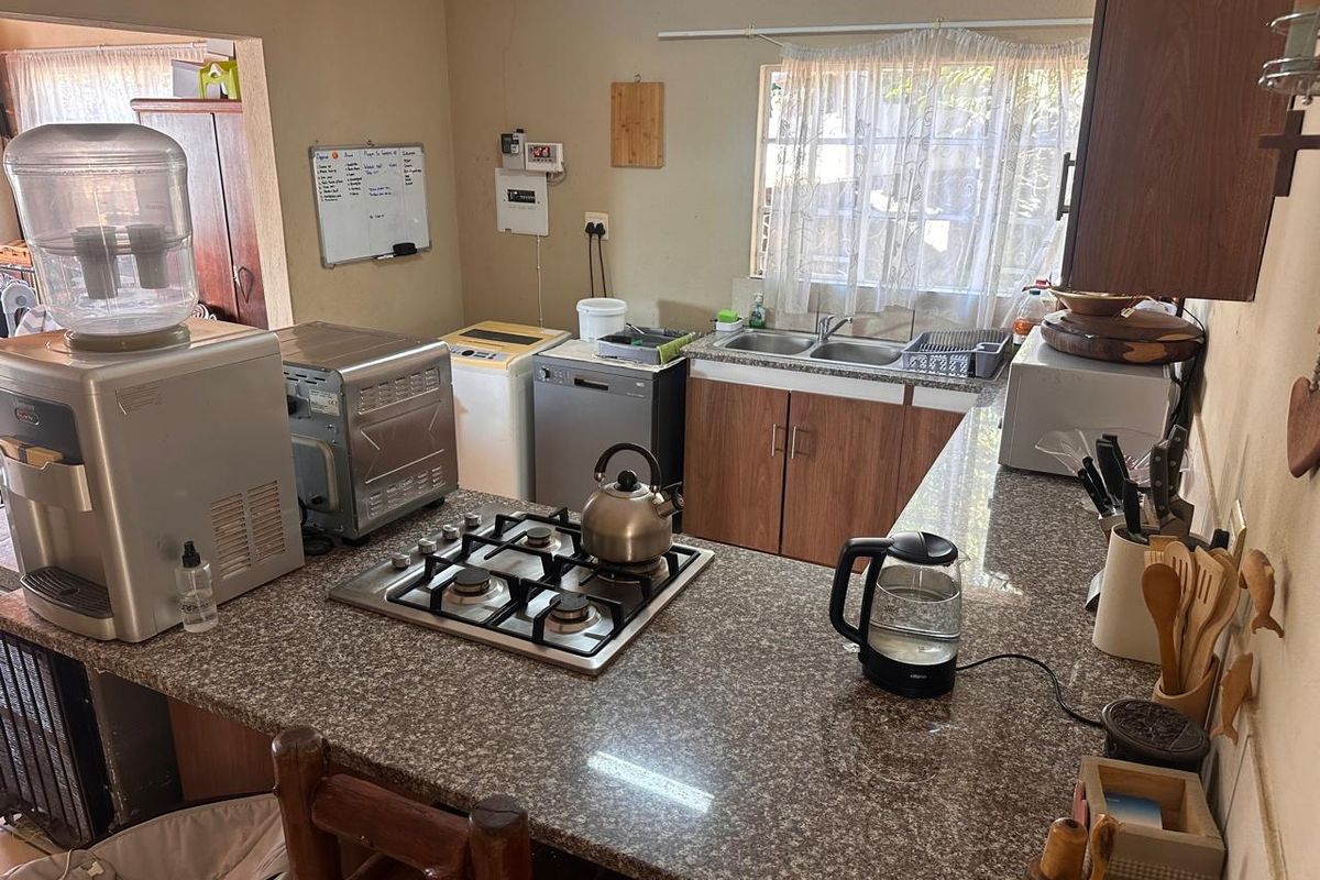 Functional kitchen featuring granite countertops, a built-in gas hob, and wooden cabinetry, offering a practical layout for daily meal preparation.