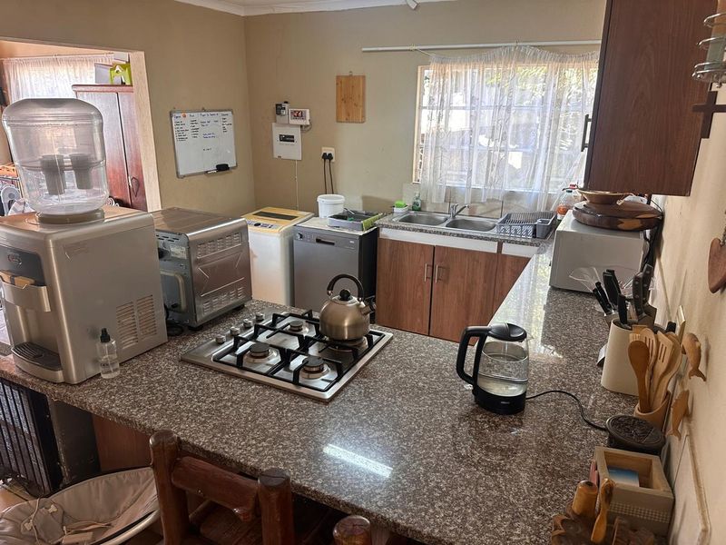 Functional kitchen featuring granite countertops, a built-in gas hob, and wooden cabinetry, offering a practical layout for daily meal preparation.